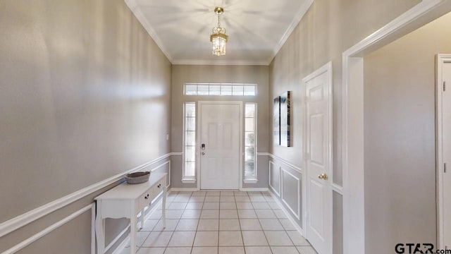 foyer featuring light tile patterned floors, a wainscoted wall, crown molding, and a decorative wall