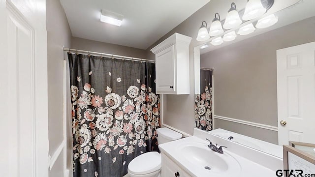 bathroom with curtained shower, toilet, and vanity