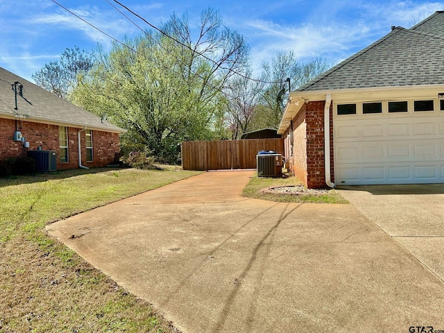 view of home's exterior with brick siding, central air condition unit, a lawn, and a garage