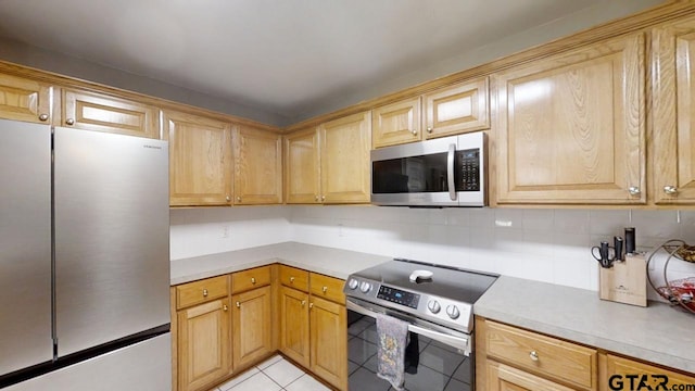 kitchen featuring light countertops, light tile patterned floors, backsplash, and appliances with stainless steel finishes