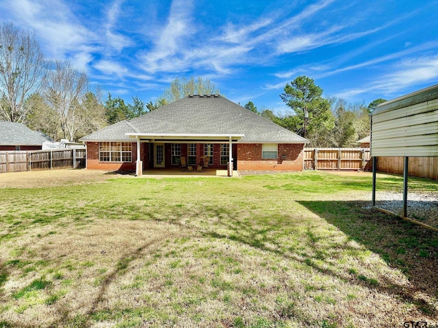 rear view of house with a patio area, a lawn, brick siding, and a fenced backyard