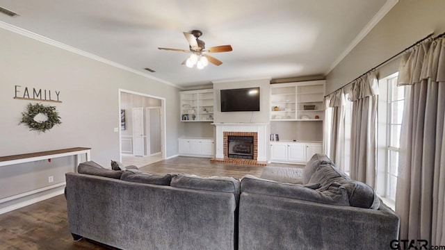 living area featuring visible vents, dark wood-style floors, crown molding, a brick fireplace, and ceiling fan