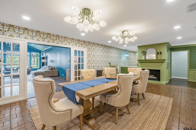 dining space featuring brick floor, a notable chandelier, recessed lighting, visible vents, and wallpapered walls