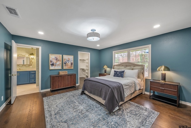 bedroom featuring baseboards, visible vents, connected bathroom, hardwood / wood-style flooring, and recessed lighting