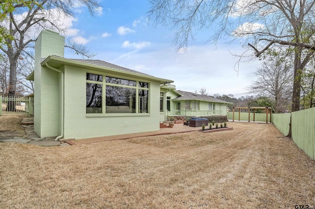 rear view of house featuring brick siding, roof with shingles, a chimney, a patio area, and a fenced backyard