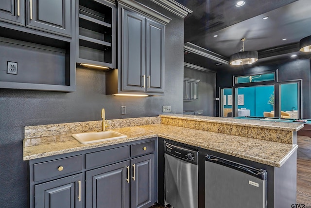 kitchen featuring dark wood-style flooring, a textured wall, stainless steel dishwasher, a sink, and a peninsula