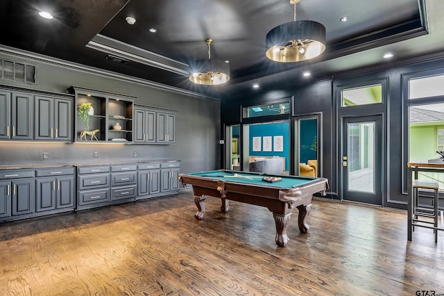 game room with dark wood-type flooring, a raised ceiling, and crown molding