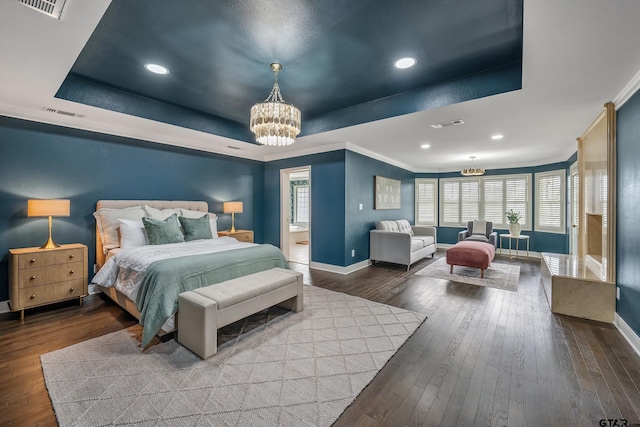 bedroom featuring hardwood / wood-style flooring, baseboards, a tray ceiling, and a chandelier