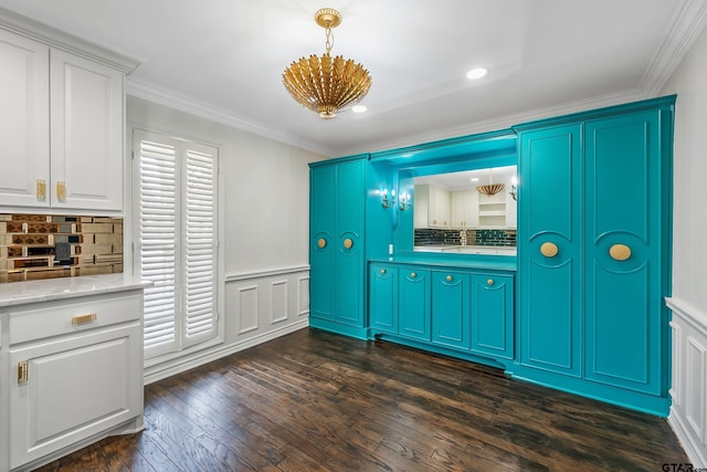 interior space featuring a wainscoted wall, ornamental molding, backsplash, dark wood finished floors, and decorative light fixtures