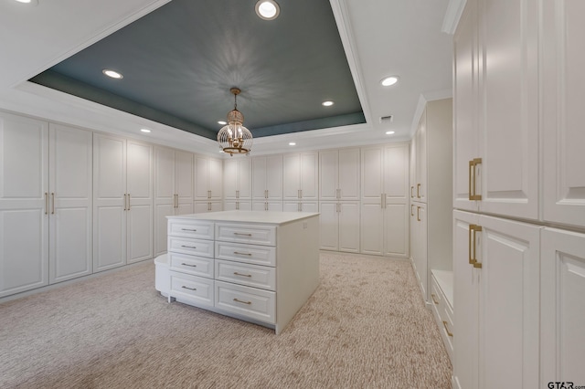 walk in closet with a tray ceiling, light colored carpet, a notable chandelier, and visible vents