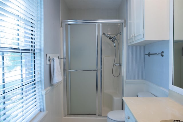 3505 Cloverdale Dr, Tyler, TX 75701 - bathroom with a decorative wall, a shower stall, vanity, toilet, and wainscoting