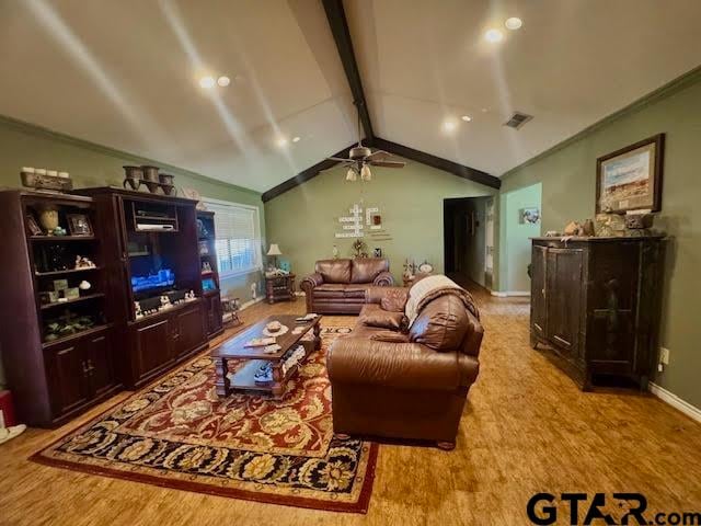 living room featuring wood finished floors, visible vents, baseboards, lofted ceiling with beams, and ornamental molding