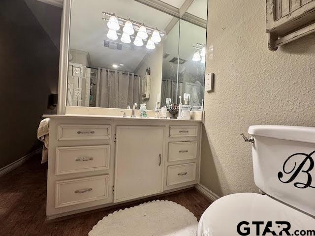 bathroom with hardwood / wood-style floors, vanity, a shower with curtain, and vaulted ceiling