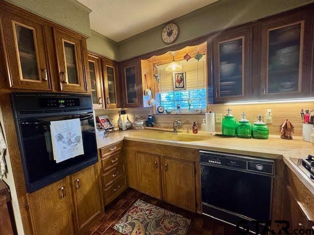 12239 Lovers Ln, Larue, TX 75770 - kitchen featuring black appliances, light countertops, glass insert cabinets, and brown cabinetry