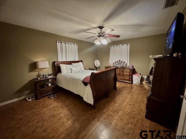 bedroom with ceiling fan, dark hardwood / wood-style floors, and a textured ceiling