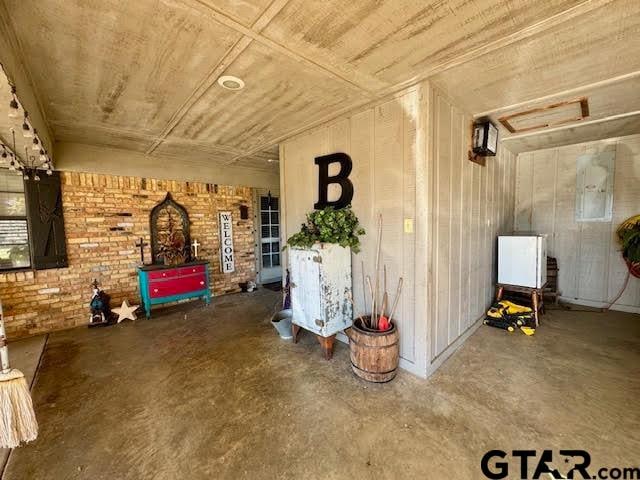 interior space with electric panel, wooden ceiling, brick wall, and concrete flooring