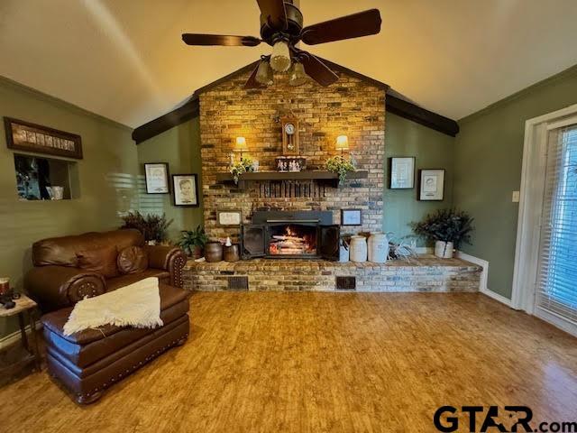 living area featuring a fireplace, crown molding, ceiling fan, and vaulted ceiling