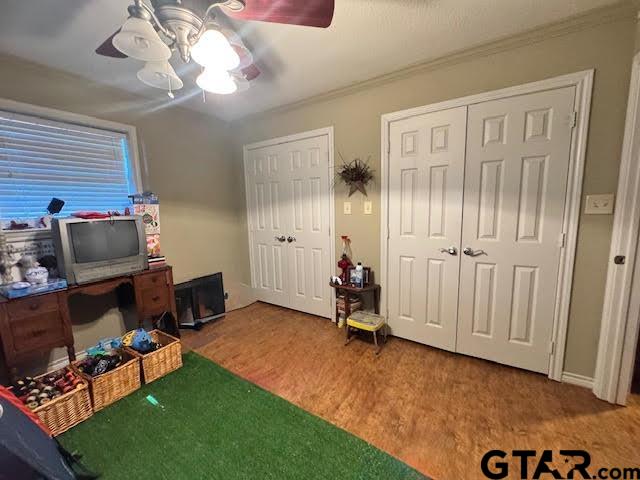 interior space featuring a ceiling fan, crown molding, and wood finished floors