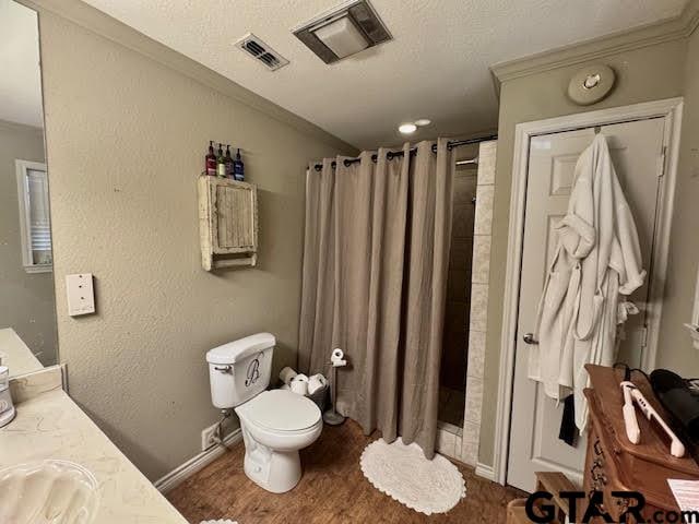 bathroom featuring vanity, crown molding, hardwood / wood-style floors, toilet, and curtained shower