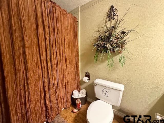 bathroom with a textured ceiling, toilet, and a textured wall