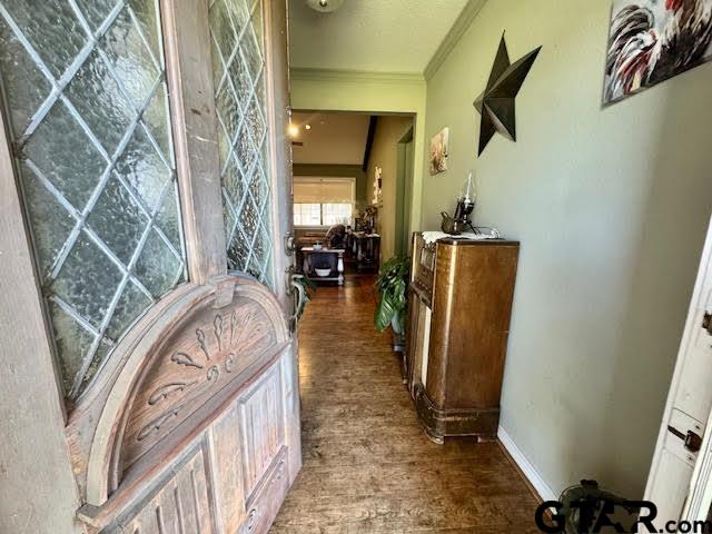 hallway featuring crown molding, wood finished floors, and baseboards