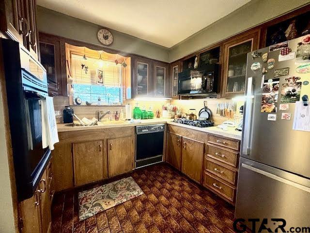 12239 Lovers Ln, Larue, TX 75770 - kitchen featuring black appliances, light countertops, glass insert cabinets, and brick patterned flooring