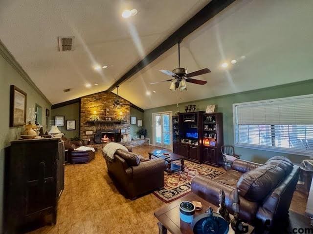 living room featuring vaulted ceiling with beams, plenty of natural light, ceiling fan, and a stone fireplace