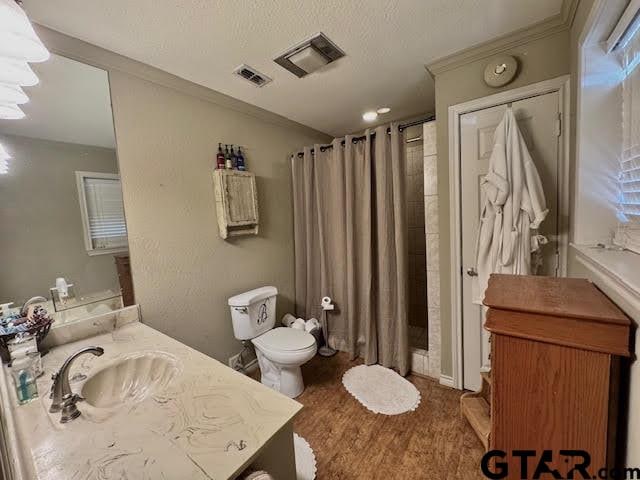 bathroom with a shower with shower curtain, vanity, crown molding, hardwood / wood-style floors, and toilet