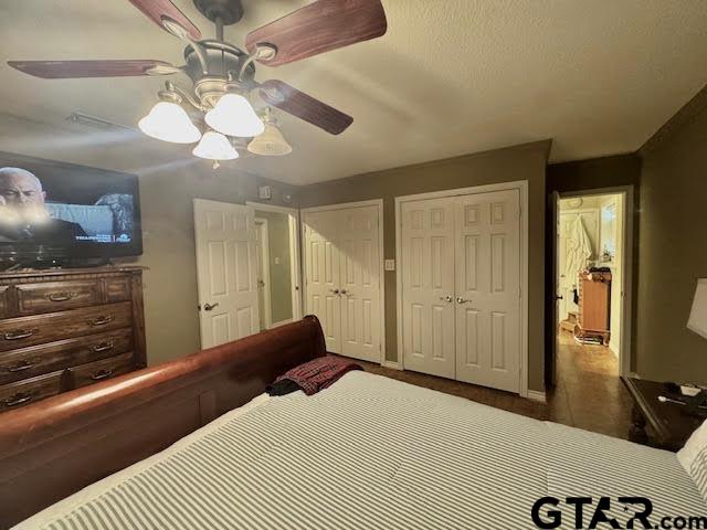 bedroom with ceiling fan and multiple closets