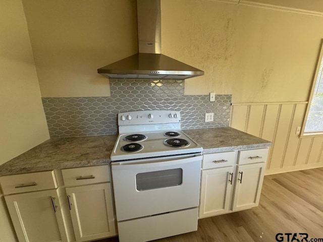 kitchen with wall chimney range hood, decorative backsplash, white electric range oven, light hardwood / wood-style floors, and white cabinetry