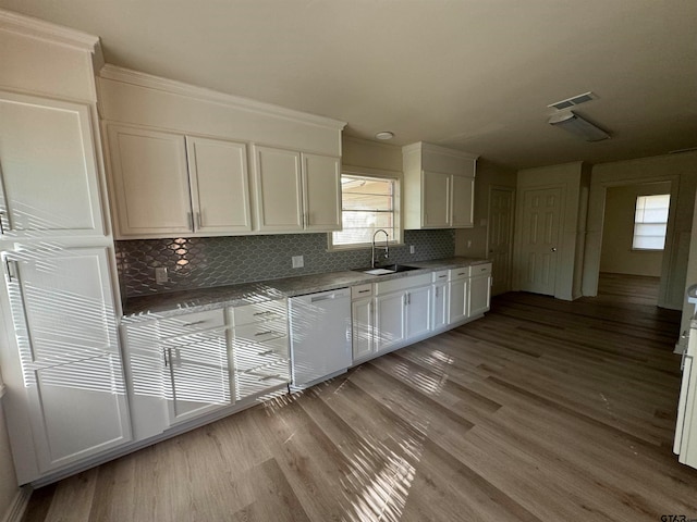 kitchen featuring sink, light hardwood / wood-style flooring, backsplash, white dishwasher, and white cabinets