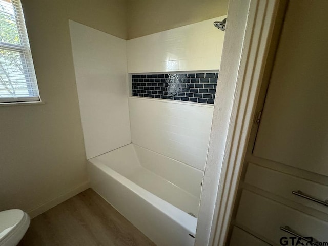 bathroom with hardwood / wood-style floors, toilet, and tiled shower / bath