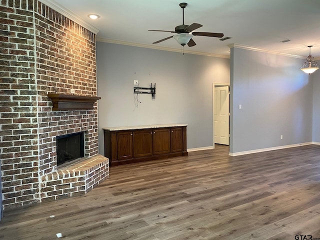 unfurnished living room featuring dark hardwood / wood-style floors, ornamental molding, and a brick fireplace