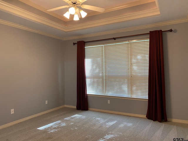 carpeted spare room with a tray ceiling, ceiling fan, and ornamental molding