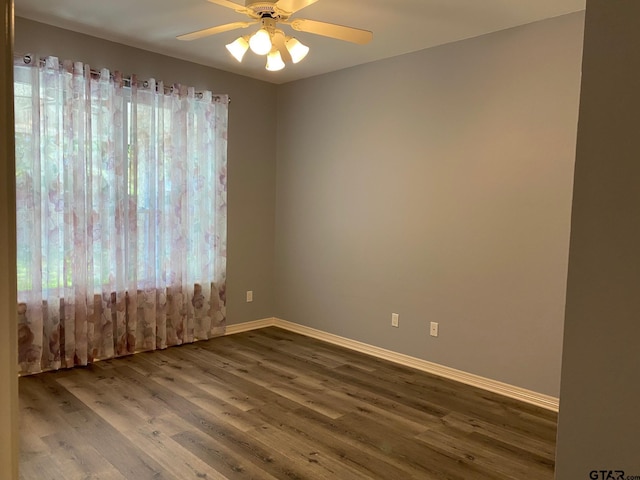 empty room with dark hardwood / wood-style flooring, ceiling fan, and a healthy amount of sunlight