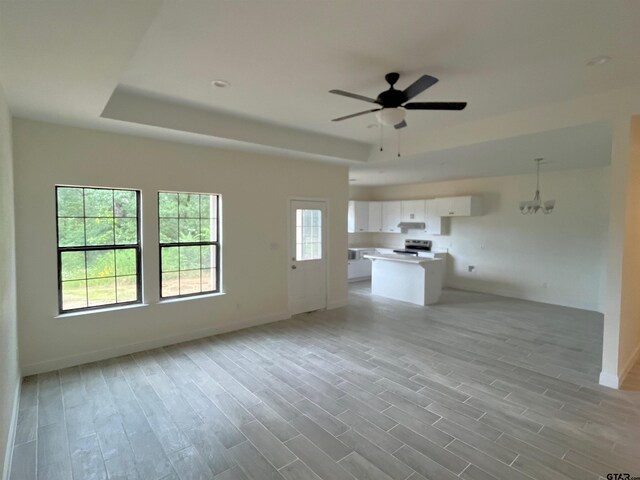 225 S Quille Ave, Mount Pleasant, TX 75455 - unfurnished living room featuring a raised ceiling, ceiling fan, light wood finished floors, and baseboards