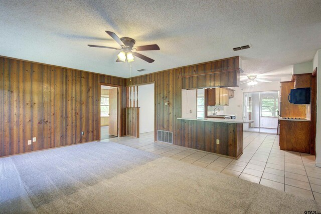 19870 Fm 1253, Lindale, TX 75771 - kitchen with a ceiling fan, light tile patterned floors, wood walls, light countertops, and a textured ceiling
