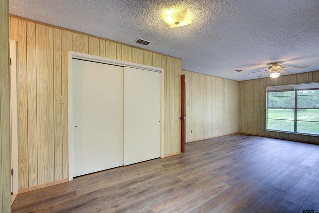 19870 Fm 1253, Lindale, TX 75771 - unfurnished bedroom with wood finished floors, a textured ceiling, a closet, wooden walls, and a ceiling fan