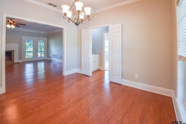 spare room featuring french doors, wood-type flooring, ornamental molding, and ceiling fan with notable chandelier