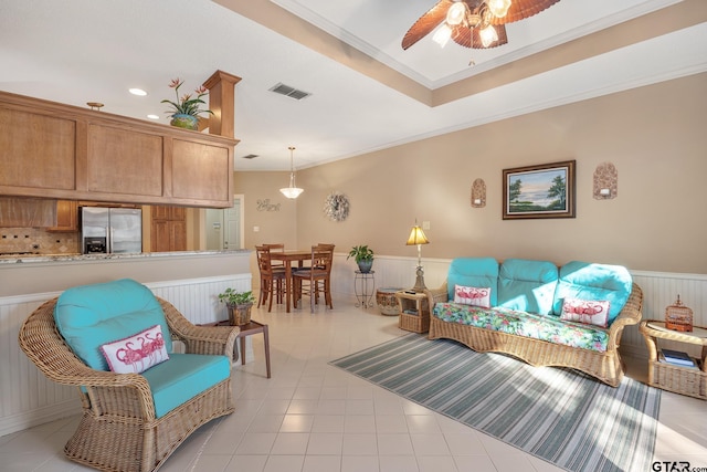 living room featuring ceiling fan, light tile patterned flooring, a raised ceiling, and ornamental molding