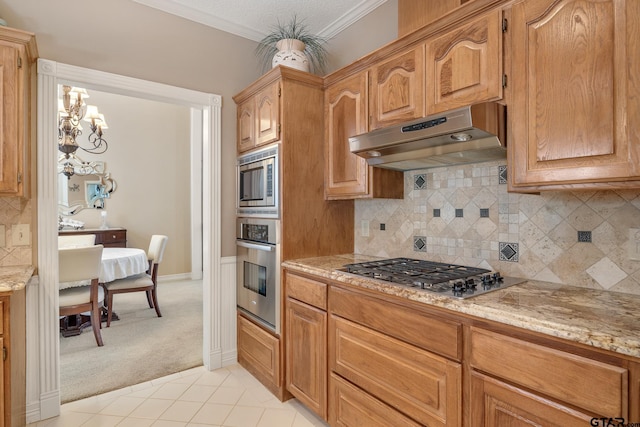 kitchen with light stone countertops, stainless steel appliances, decorative backsplash, light tile patterned floors, and ornamental molding