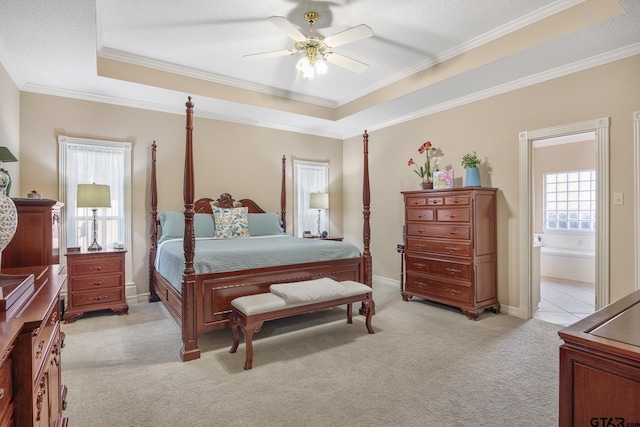 carpeted bedroom with ceiling fan, a raised ceiling, ornamental molding, and ensuite bathroom