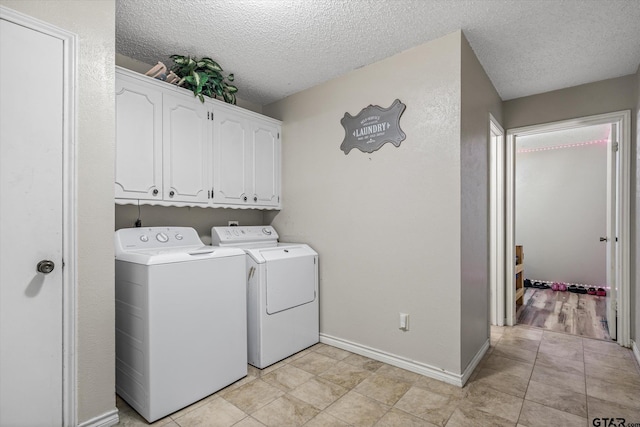 washroom with washer and dryer, baseboards, cabinet space, and a textured ceiling