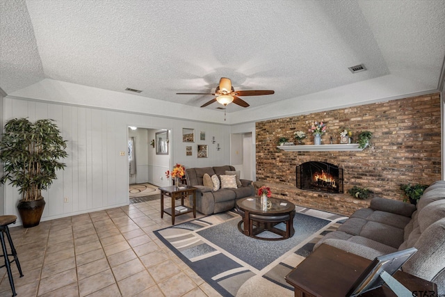 living area with light tile patterned floors, visible vents, a textured ceiling, and a brick fireplace