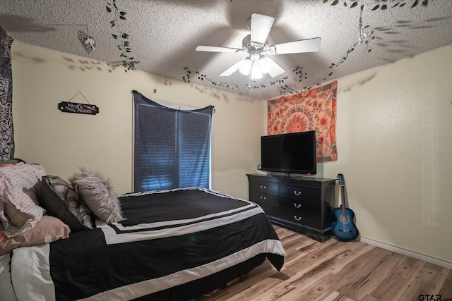 bedroom with baseboards, light wood-style flooring, ceiling fan, rail lighting, and a textured ceiling