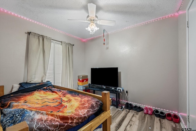 bedroom featuring a ceiling fan, wood finished floors, and a textured ceiling