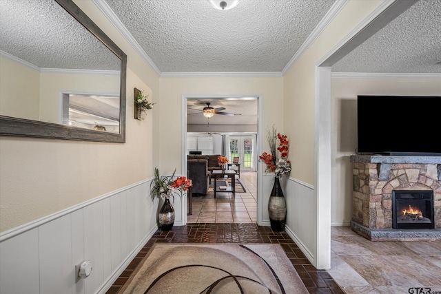 hall featuring wainscoting, a textured ceiling, and crown molding