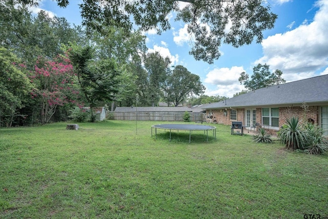 view of yard with a trampoline and fence