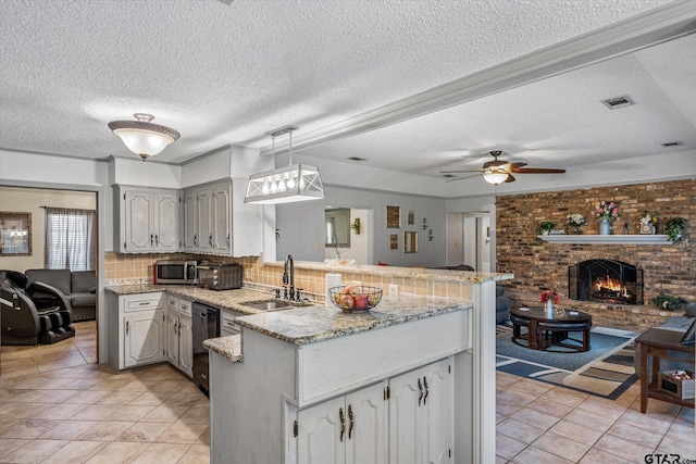 kitchen featuring stainless steel microwave, visible vents, dishwasher, a peninsula, and a sink