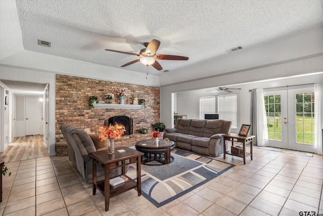 living room featuring light tile patterned floors, a fireplace, visible vents, and french doors